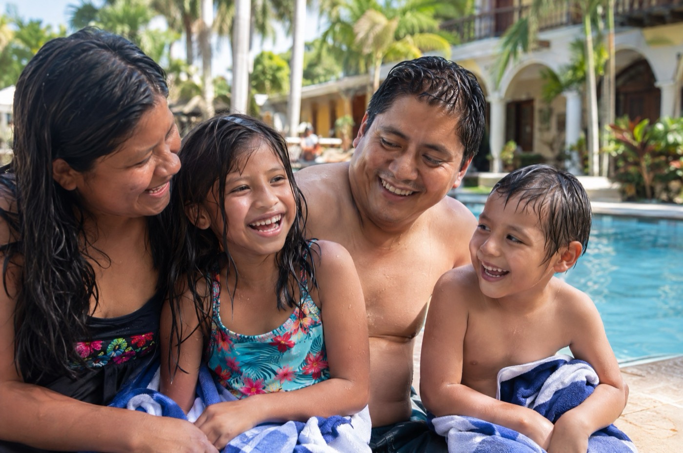 Familia riendo a la orilla de la piscina